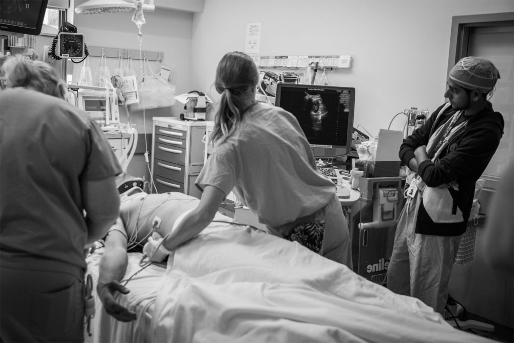 A resident uses FAST (focused assessment with sonography in trauma) on the patient's abdomen to examine for possible injuries.