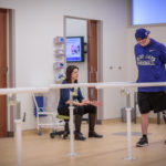 A clinician examines a patient’s walking patterns with their prosthetic leg