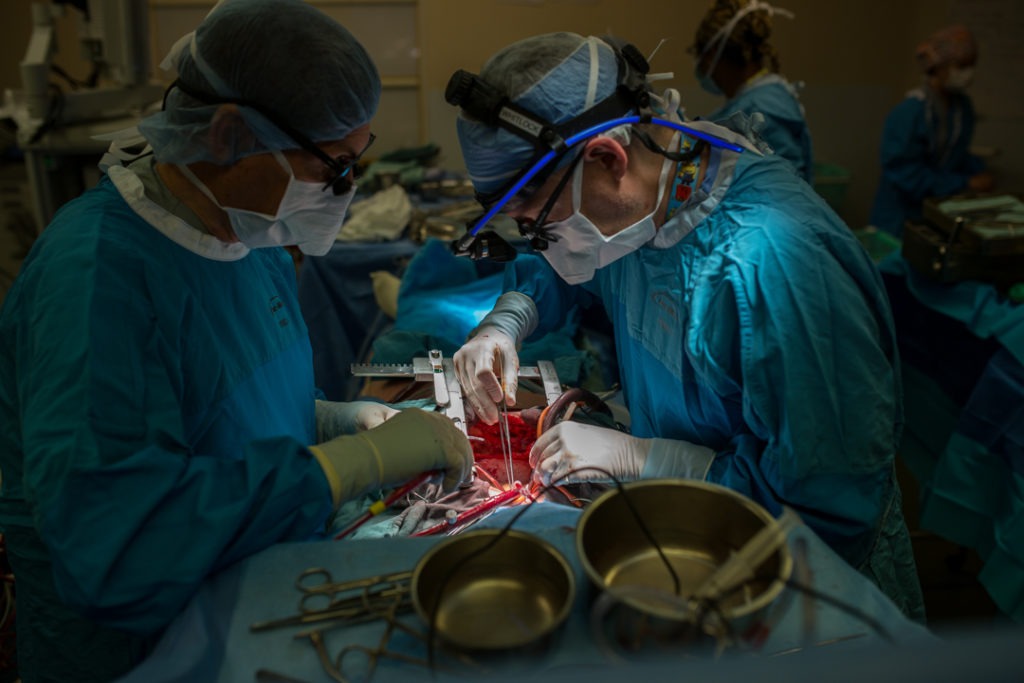 Dr. John Wells and Dr. Richard Whitlock prepare the patient for the bypass graft. The vein taken from the patient’s leg will be attached to the side of their heart to create a new pathway for blood to flow around the blocked vessel.