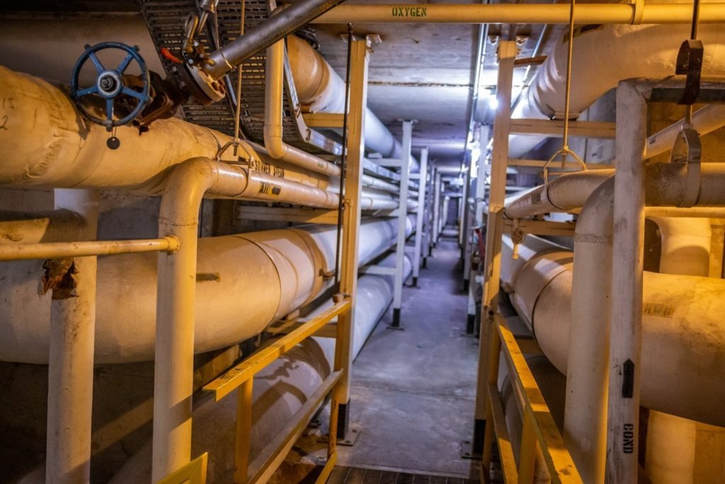 long tunnel with large pipes holding steam and chilled water
