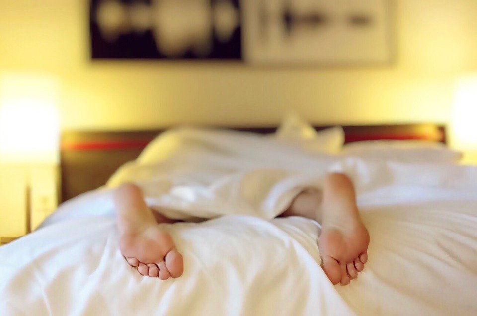 a person is lying face down in bed with their feet poking out from the covers