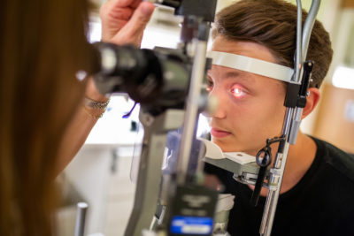 Dr. Isaza looks at Alex's eyes using a special light.