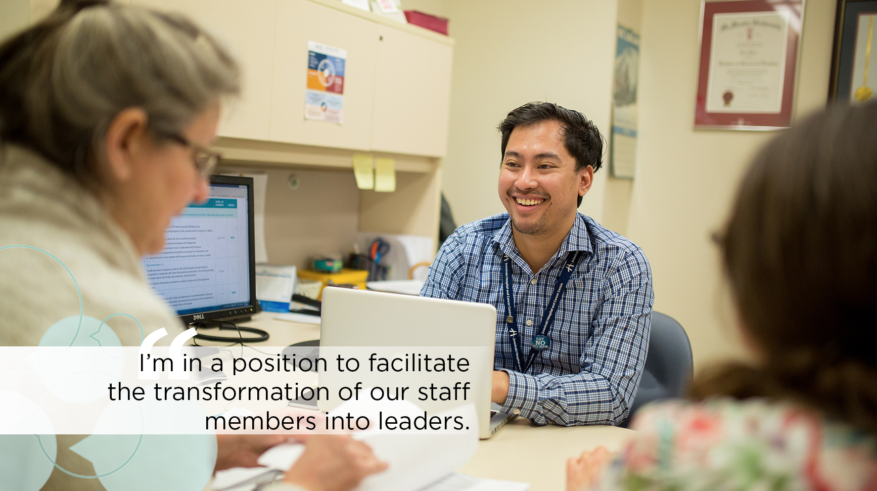 A clinical leader sits at a desk with colleagues in discussion