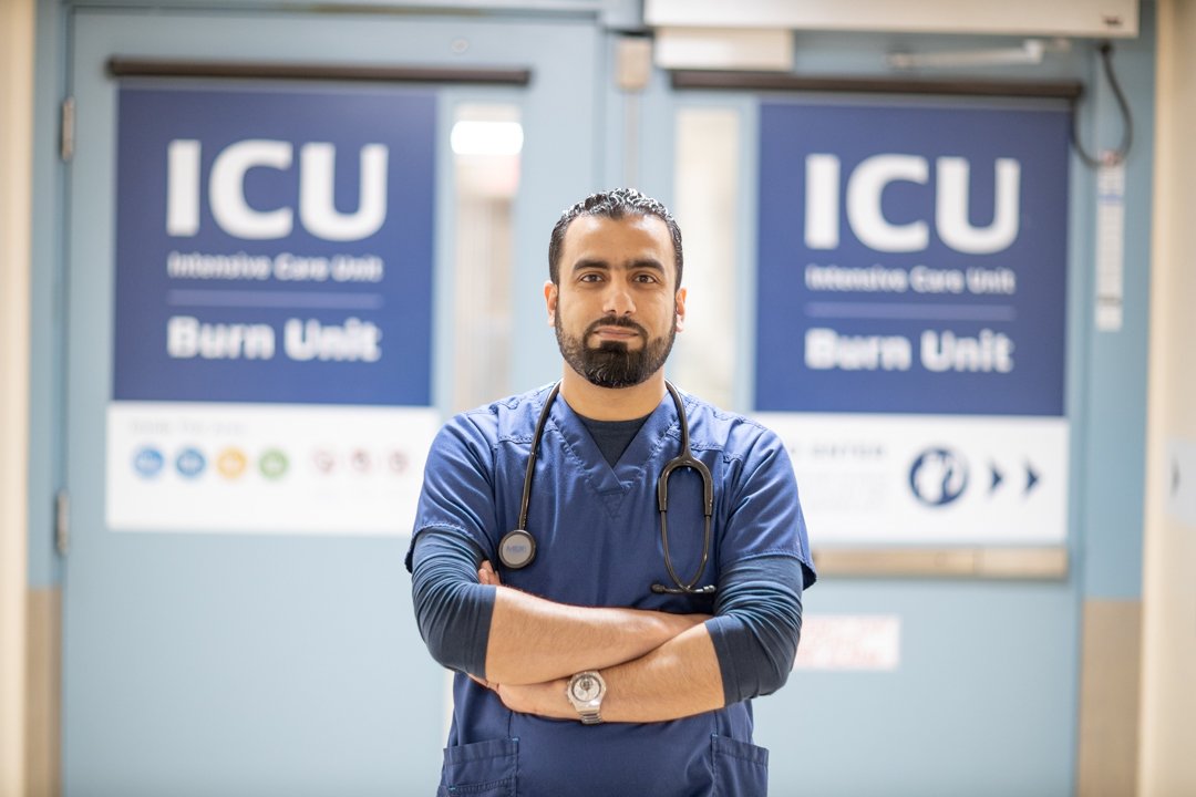 An internationally trained nurse stands in portrait in front of the ICU