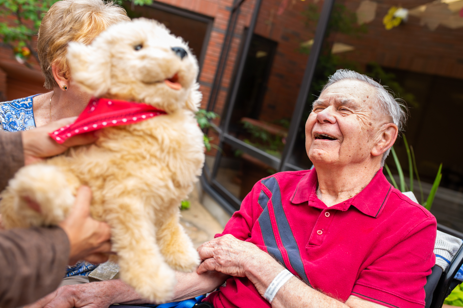 a family member holds up Daisy the robotic dog for patient, Roger, who has dementia