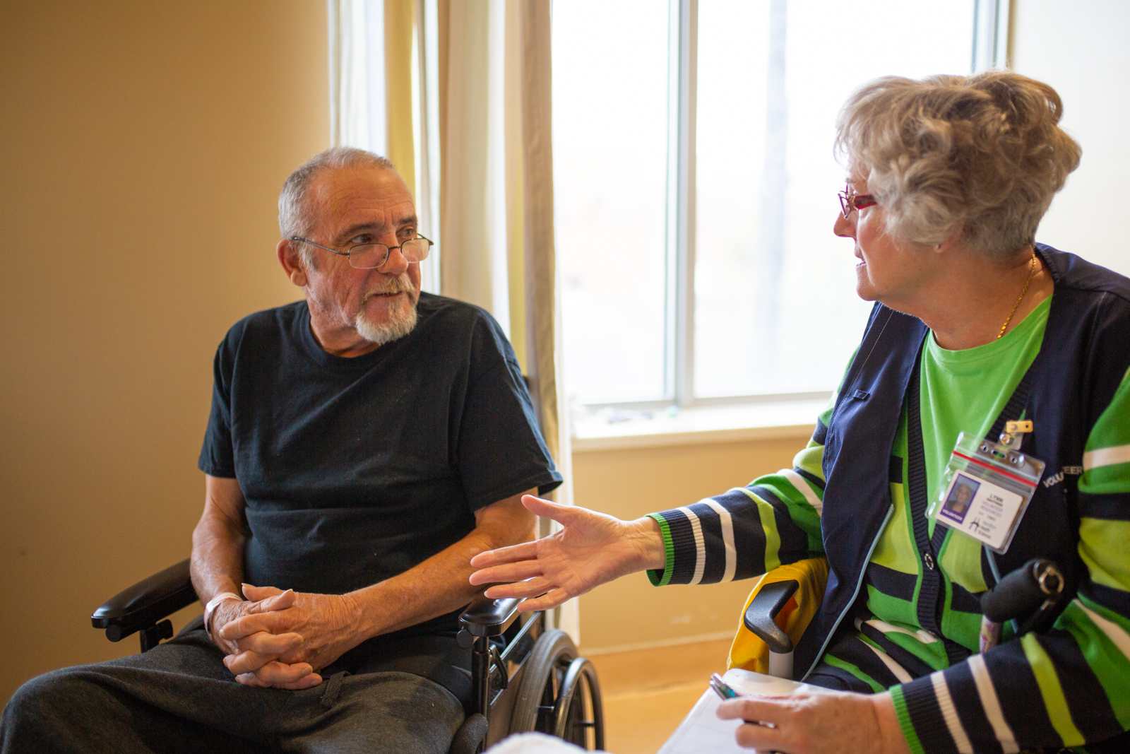 A stroke survivor speaks with a patient in recovery in a hospital room.