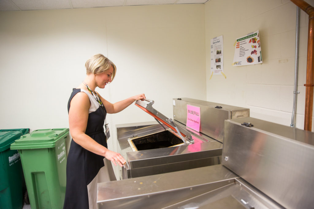 Employee putting food waste into the dehydrator to reduce our environmental impact