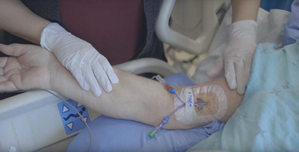 Close up of a nurse checking a central line in a patient's arm