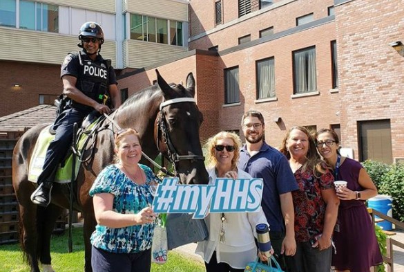 A mounted police officer stands with healthcare professionals outside a hospital