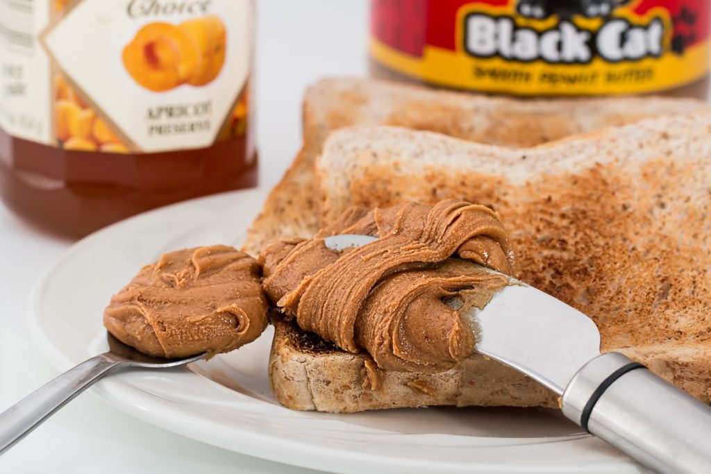 a piece of toast being spread with peanut butter
