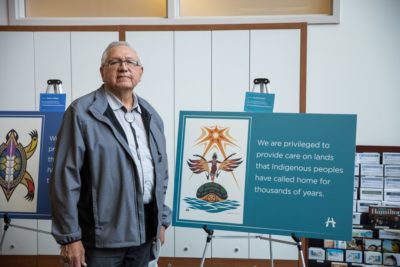 Artist, Arnold Jacobs, standing with his sign of welcome poster
