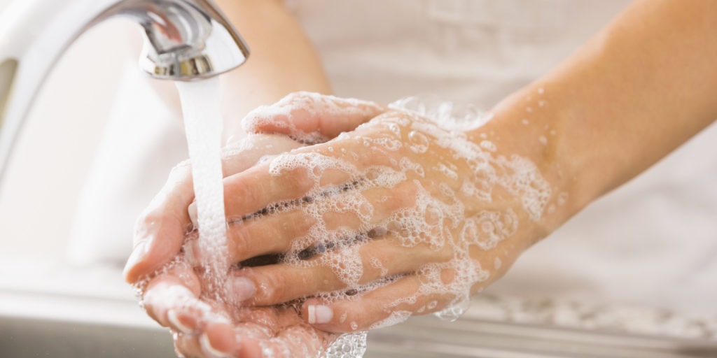 A woman washes her hands under a faucet