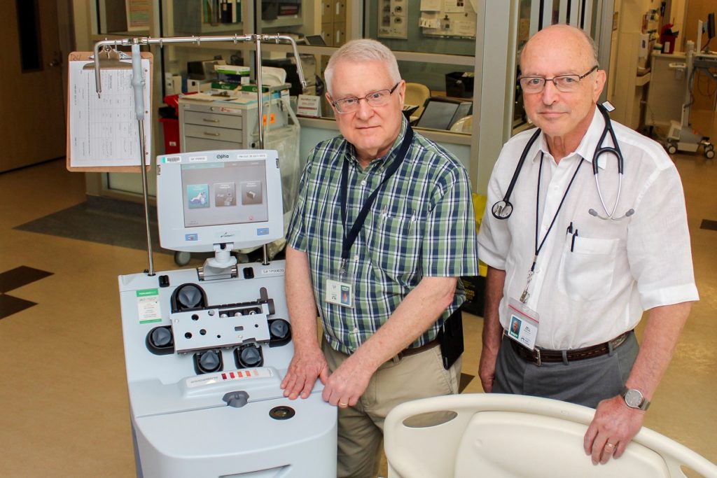 Dr. Brian Leber and Dr. Irwin Walker pose for a photo next to an apheresis machine.