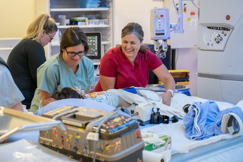 After the CT scan is complete, sedation team nurse, Rachel Gagnon and medical radiation technologist, Heather McLean, gently transfer Sophie to a stretcher so she can be moved to the next scan location, which is in the basement of the hospital.