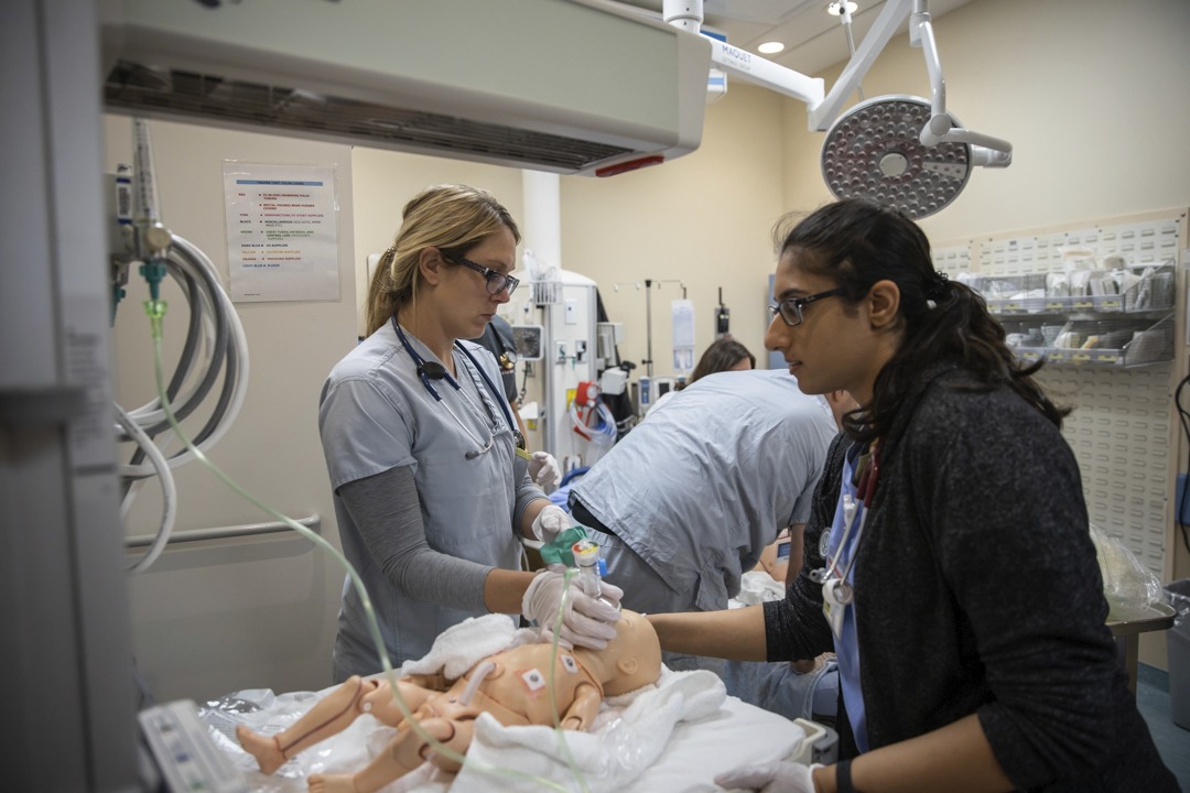Health professionals taking pretend baby's vitals