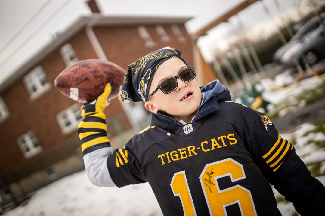 Carter Dery wearing a Ticats jersey and preparing to throw a football