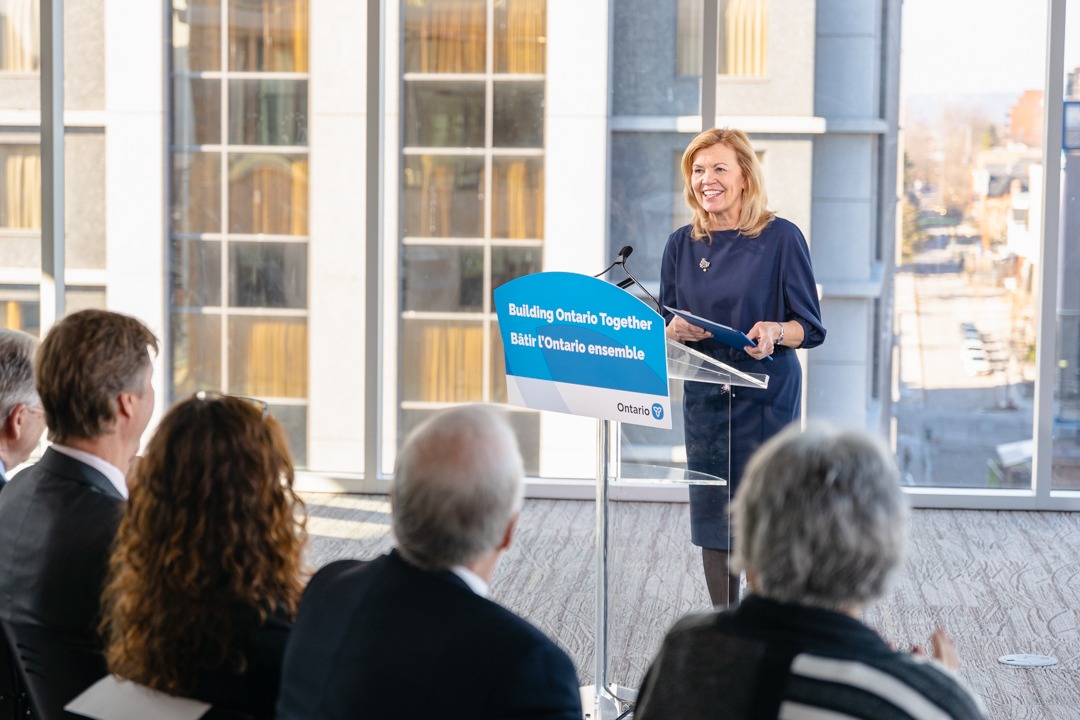 Deputy Premier and Minister of Health, the Honourable Christine Elliott stands at a podium making an announcement