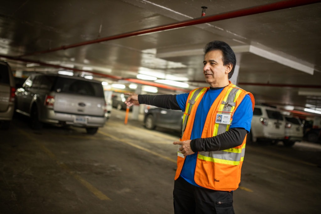A parking lot attendant directs cars in an underground garage.