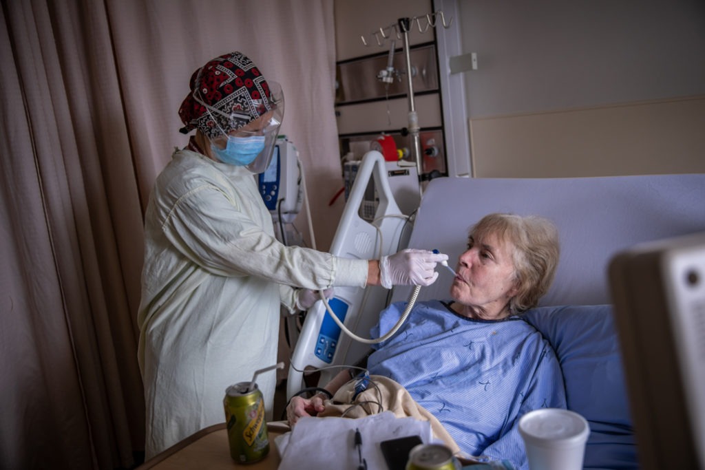 A nurse checks an elderly patients temperature with a thermometer.