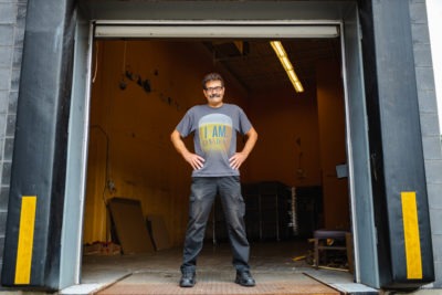 Man standing in warehouse loading dock door, hands on hips, smiling at camera