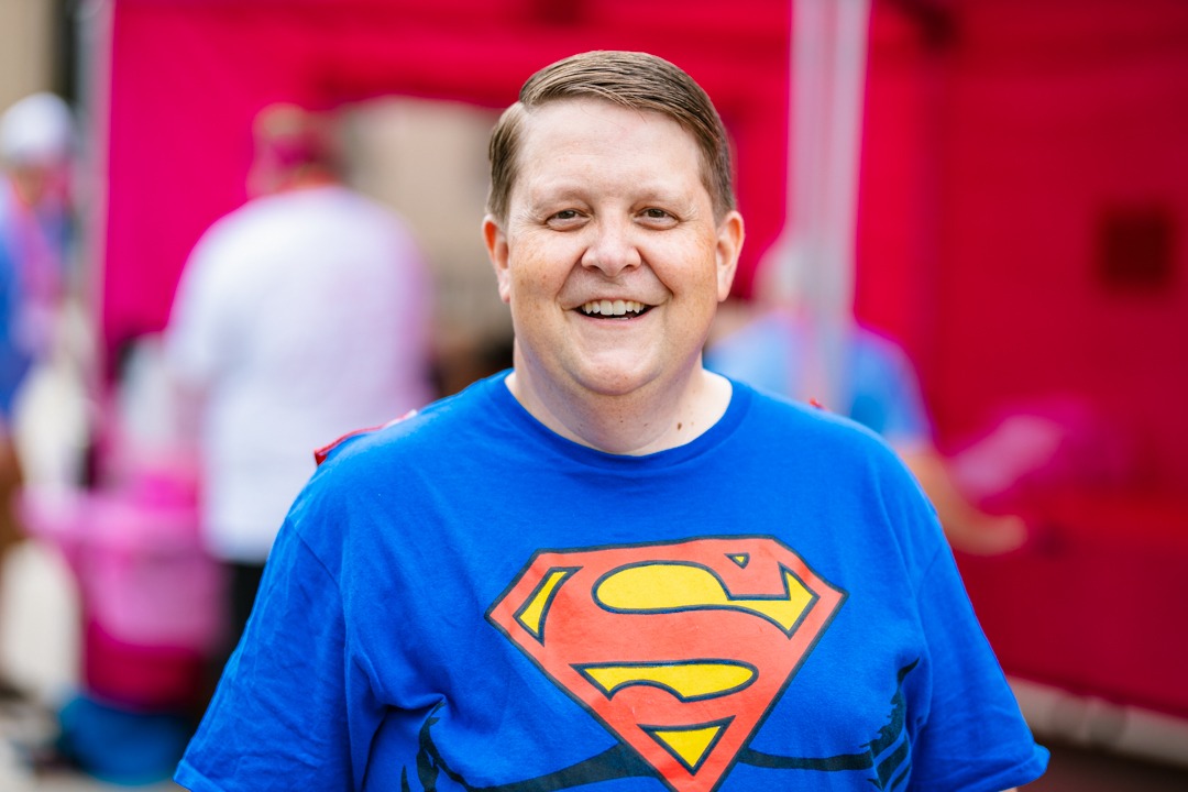 A man wearing a Superman T-shirt is smiling