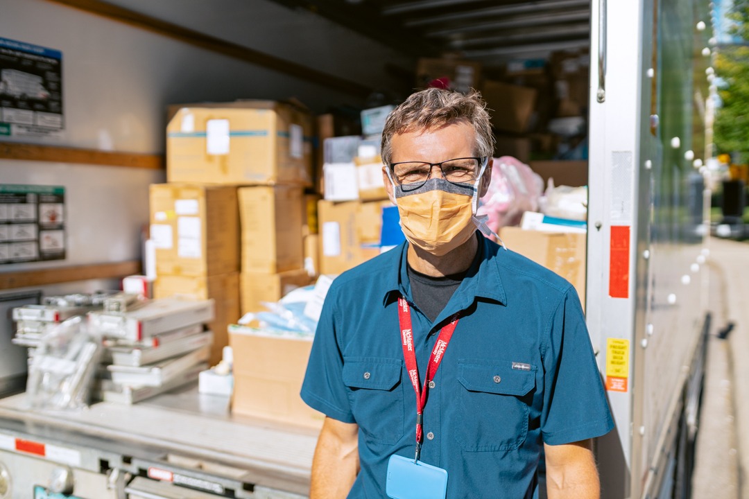 Doctor stands in front of a truck loaded with boxes of donated medical equipment