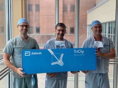 Doctors hold a poster of the new TrClip technology for repairing a leaky tricuspid valve