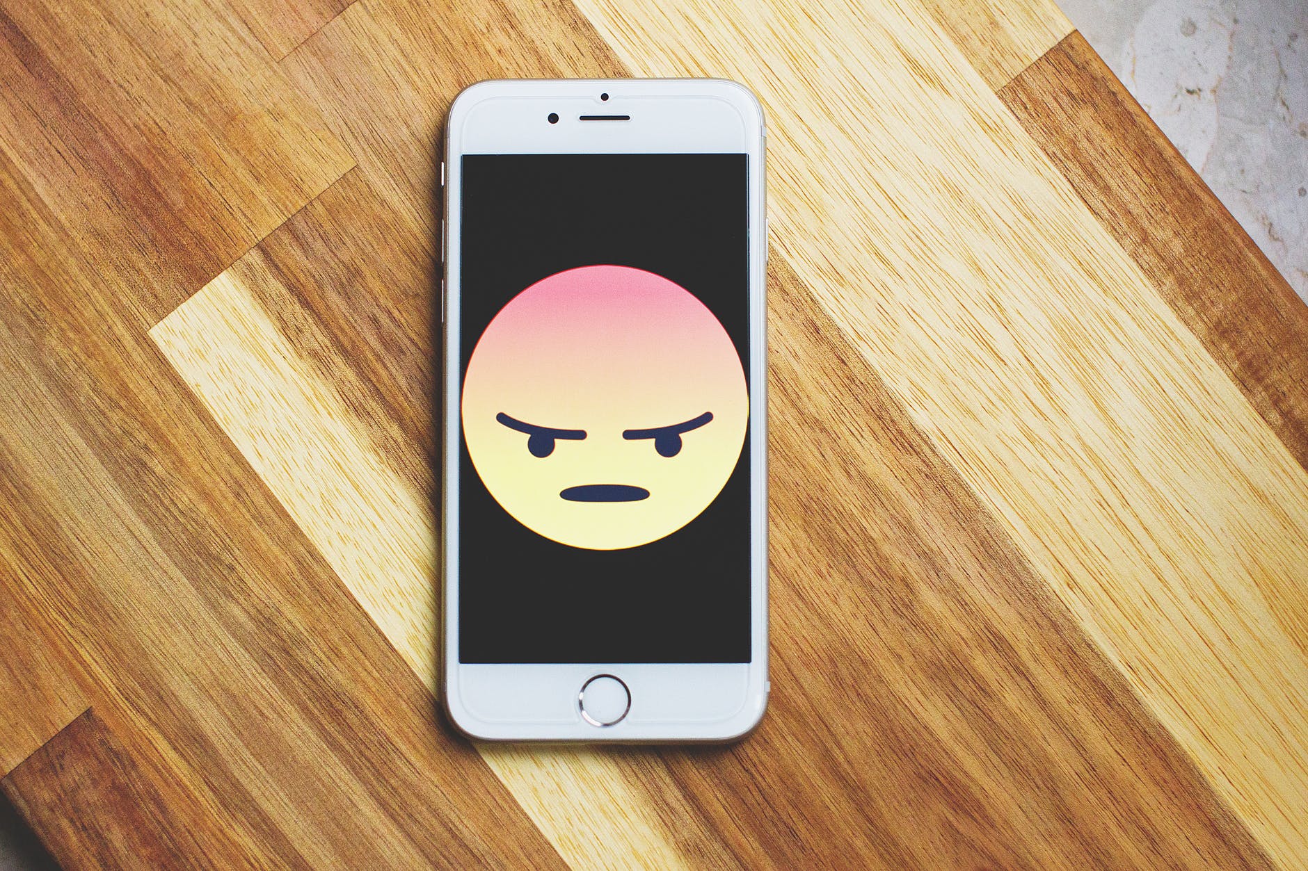 Phone with angry emoji on its screen