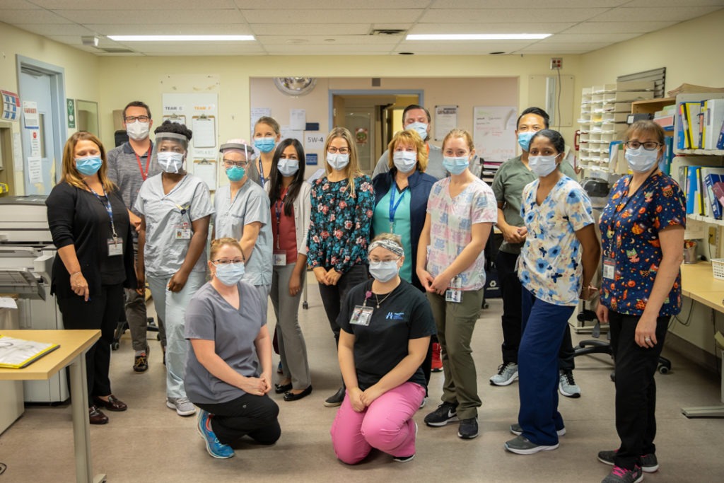 a group of health care providers stands together - spread out and masked