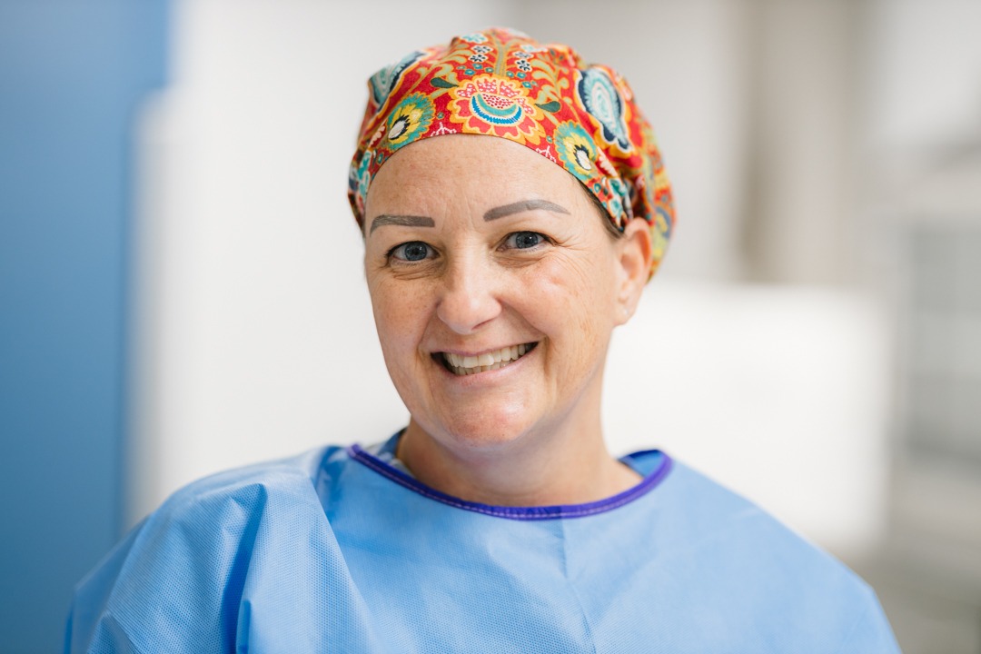 Profile photo of a woman wearing a blue scrubs top and colourful red and orange surgical cap