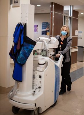 Janet Corning pushes a portable diagnostic imaging machine through the hallway.