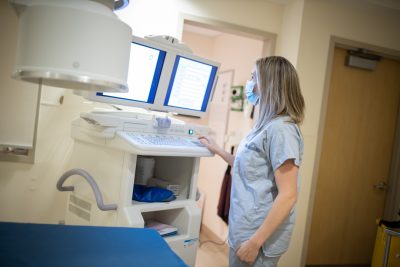 Kulla is shown on the job, using a machine in the interventional radiology area of HHS.