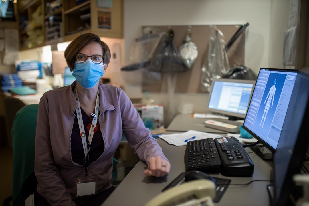 Colleen Hilbert sitting at her desk, wearing a medical face mask