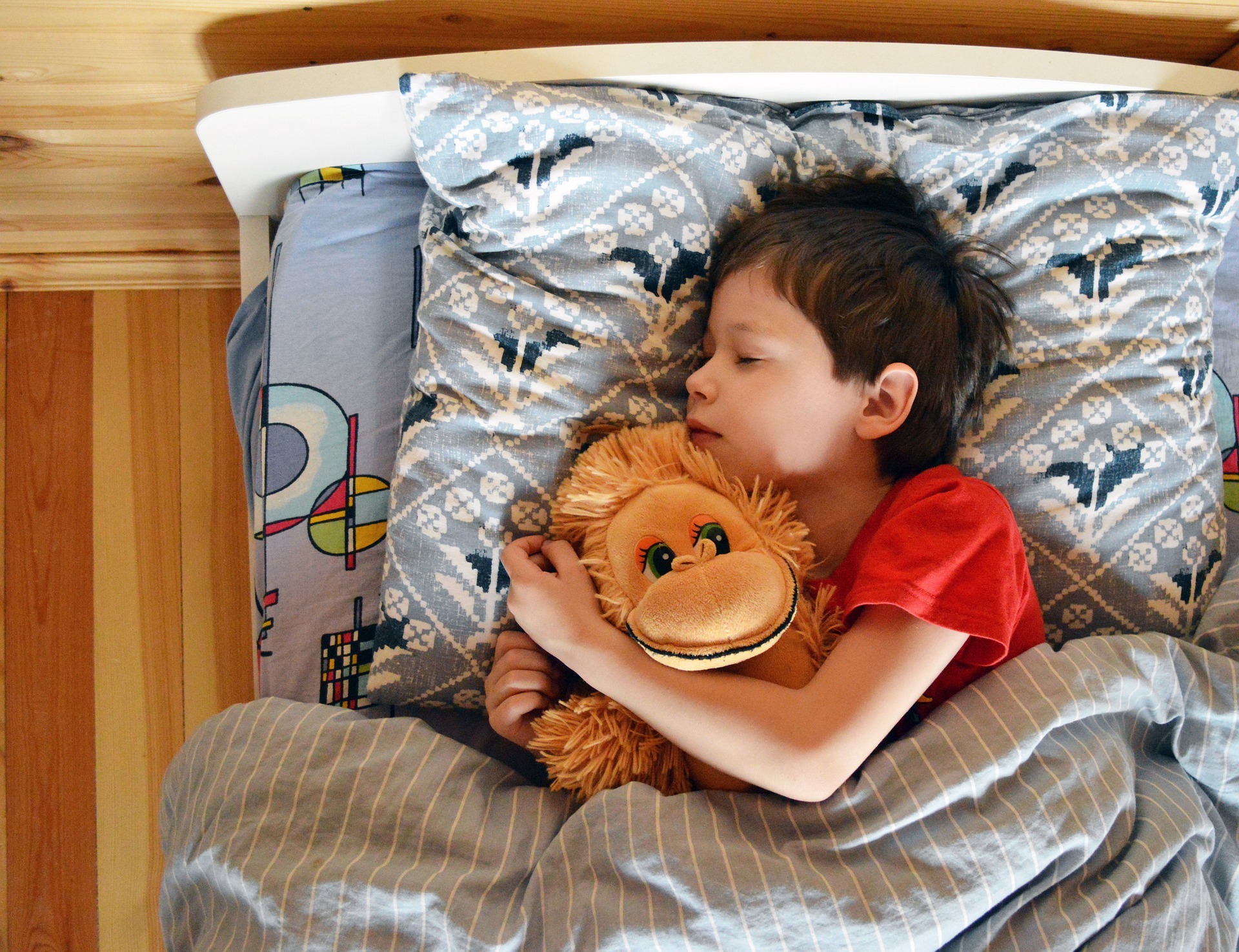 Child in bed with teddy bear