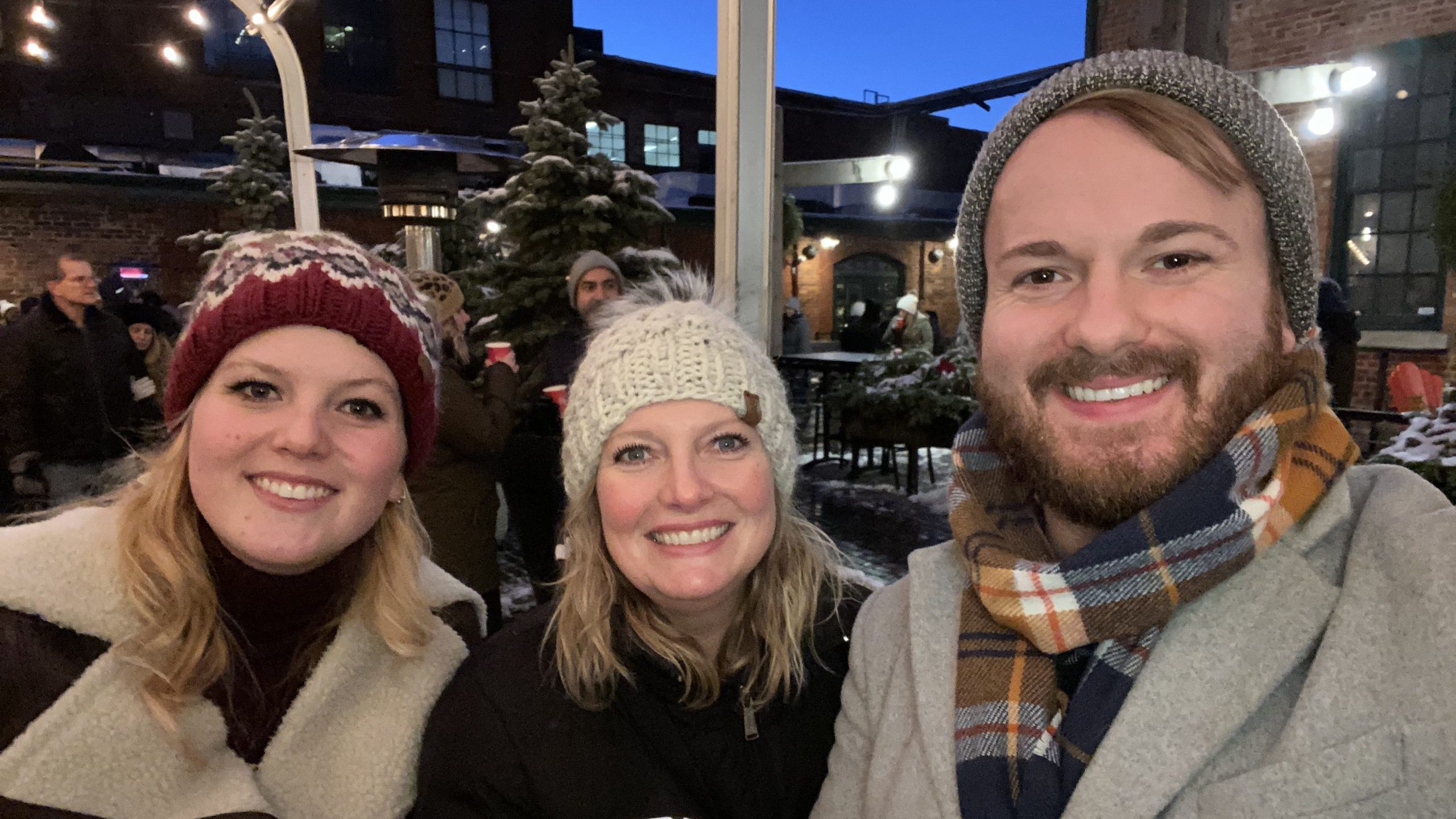 Photo of Paige, Kim, and D'Arcy Capra at an outdoor winter event. Photo taken pre-COVID.