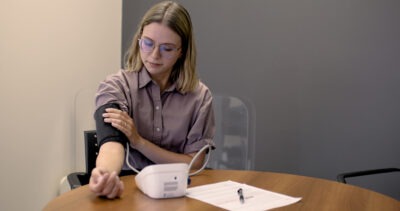 Woman putting on a the blood pressure cuff of a home monitoring kit.