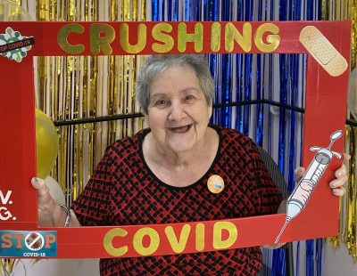 Gail holding a "crushing COVID" sign at Victoria Gardens long term care home