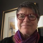 Selfie style photo of doctor Patricia Smith. Short grey hair, red glasses, purple and pink scarf.