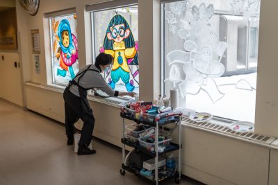 An artist works on the middle painting of a set of three windows