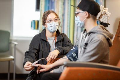 A nurse extern measures a patients blood oxygen with a fingertip sensor