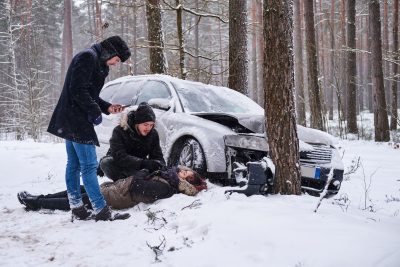 Car accident victim lies in the snow, unconscious