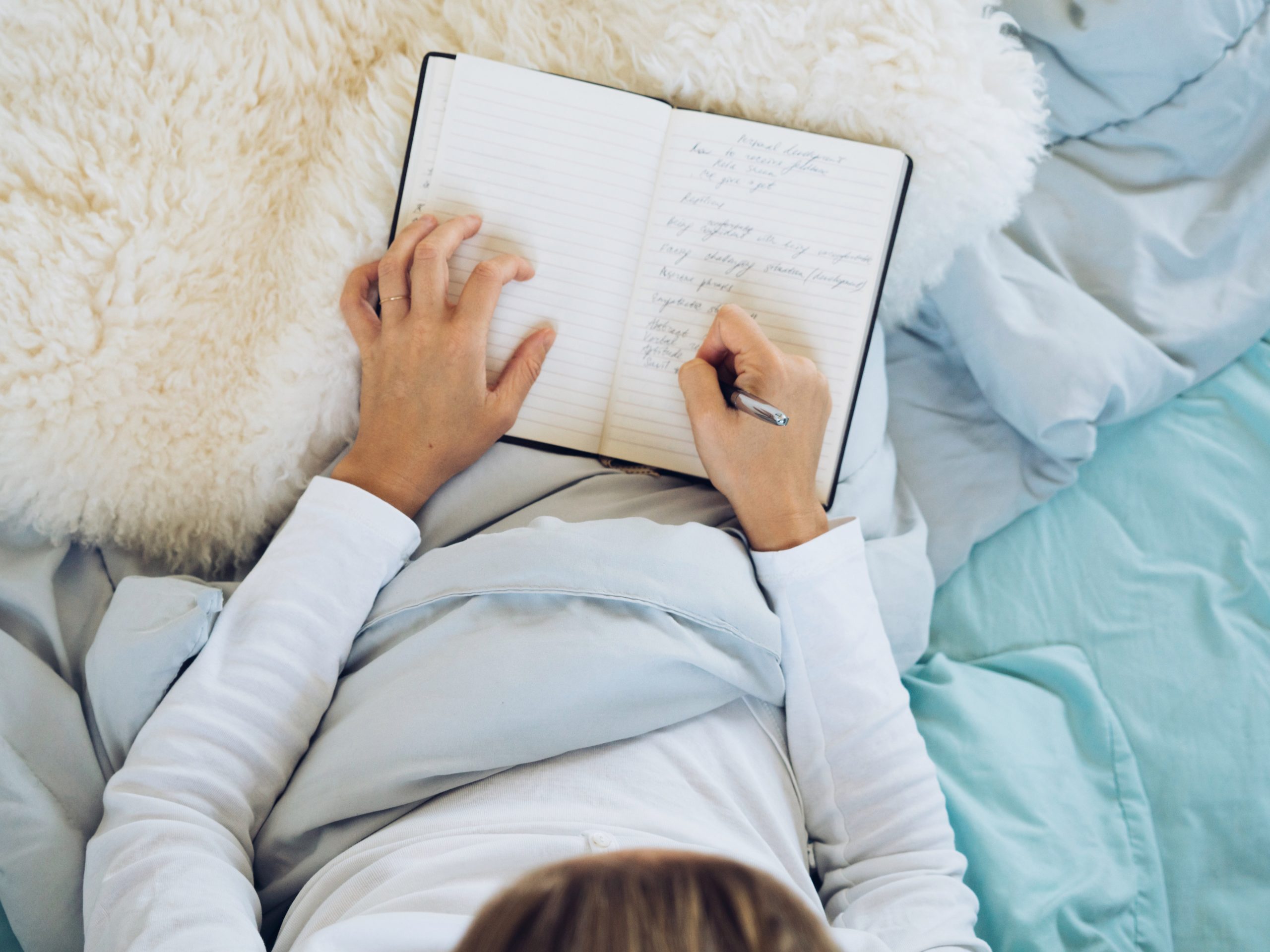 person in bed writing in journal