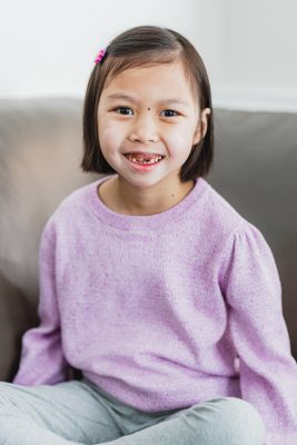 A young girl in a purple shirt, smiling