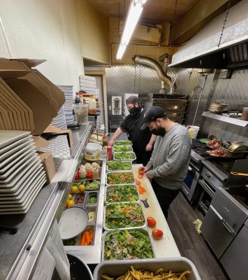 Restaurant workers in a kitchen preparing salads