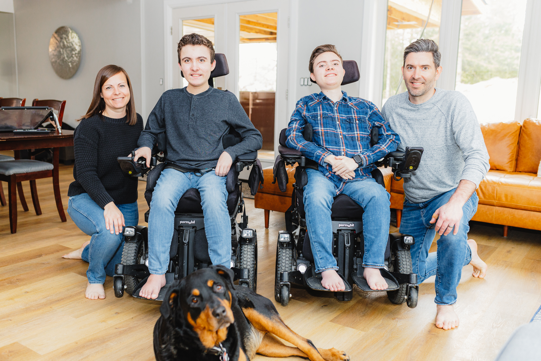 The Cavalier family pose in their living room for a family photo. From left to right are Emily, her sons Liam and Kaleb, and husband Josh. Lying in front of them is the family's tan and black large dog, Sydney