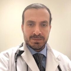 Selfie of doctor Juan Guzman, white physician's coat, dark hair and dark beard