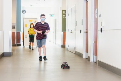 A boy operates a remote control car in a building hallway