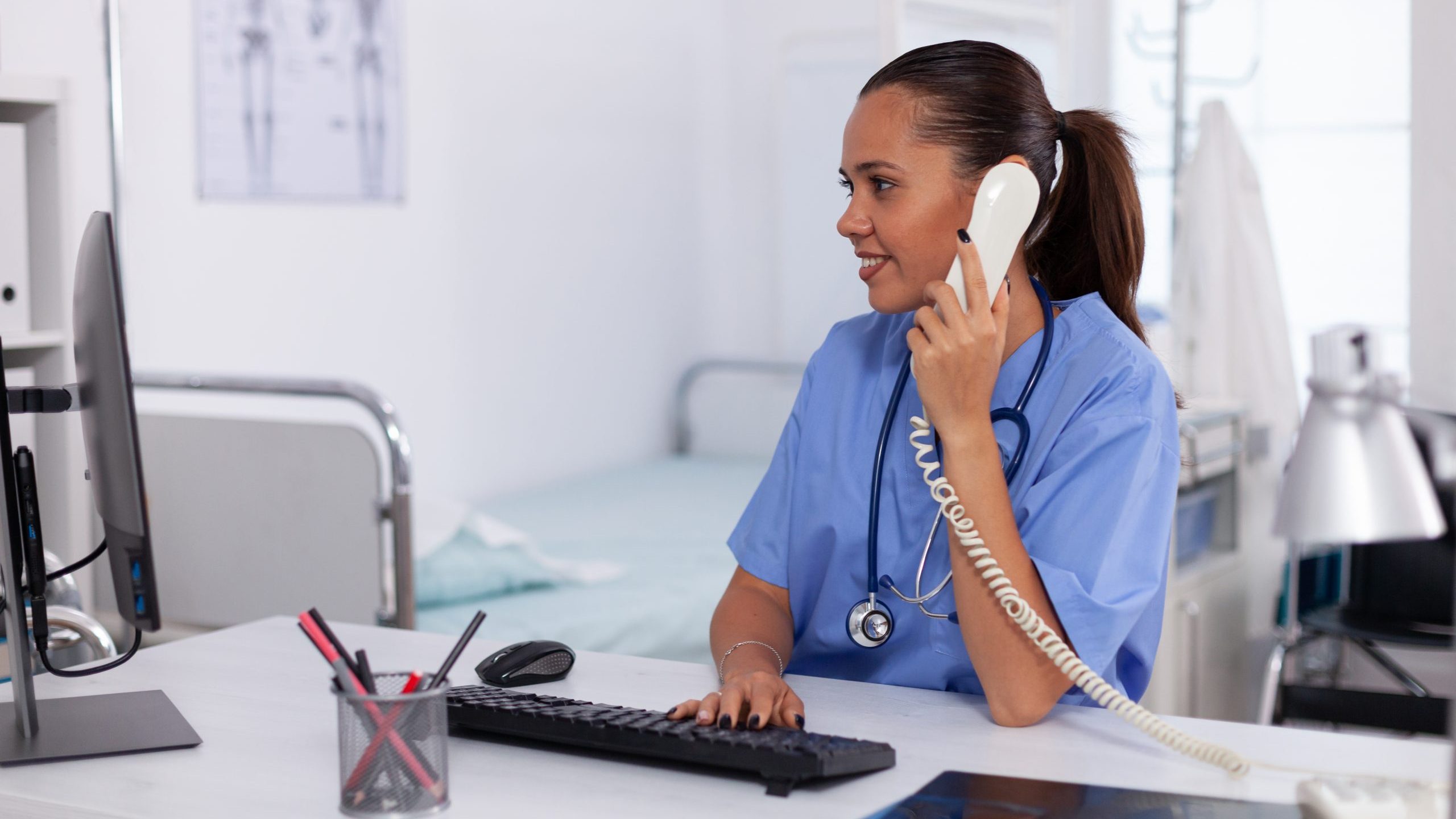 Stock photo of nurse sitting at desk and talking on phone