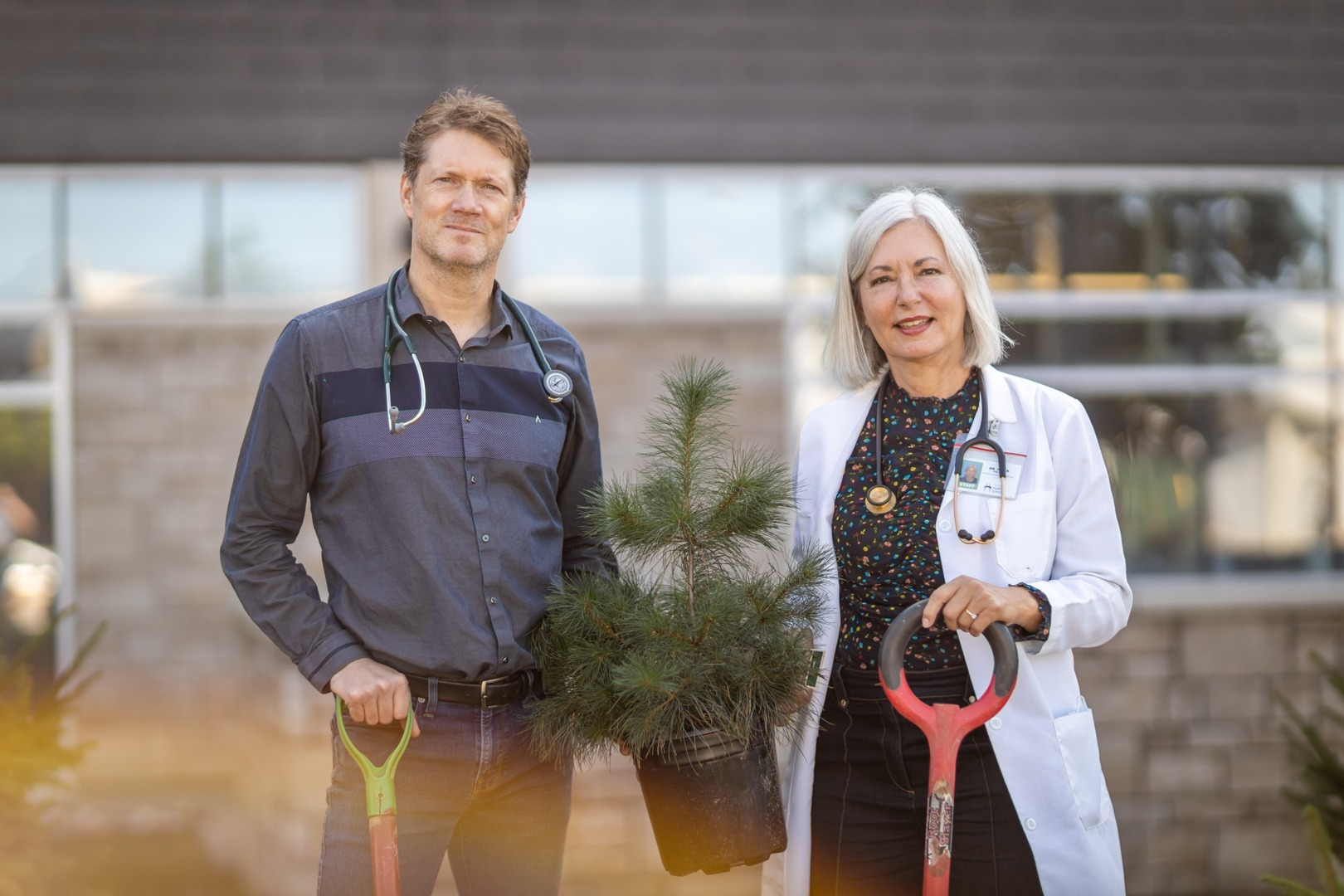 Dr. Myles Sergeant and Dr. Nora Cullen, outside Hamilton General Hospital holding a small tree and shovels