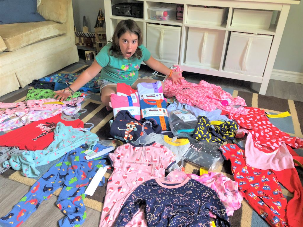 A girl sits among a large pile of donated pyjamas
